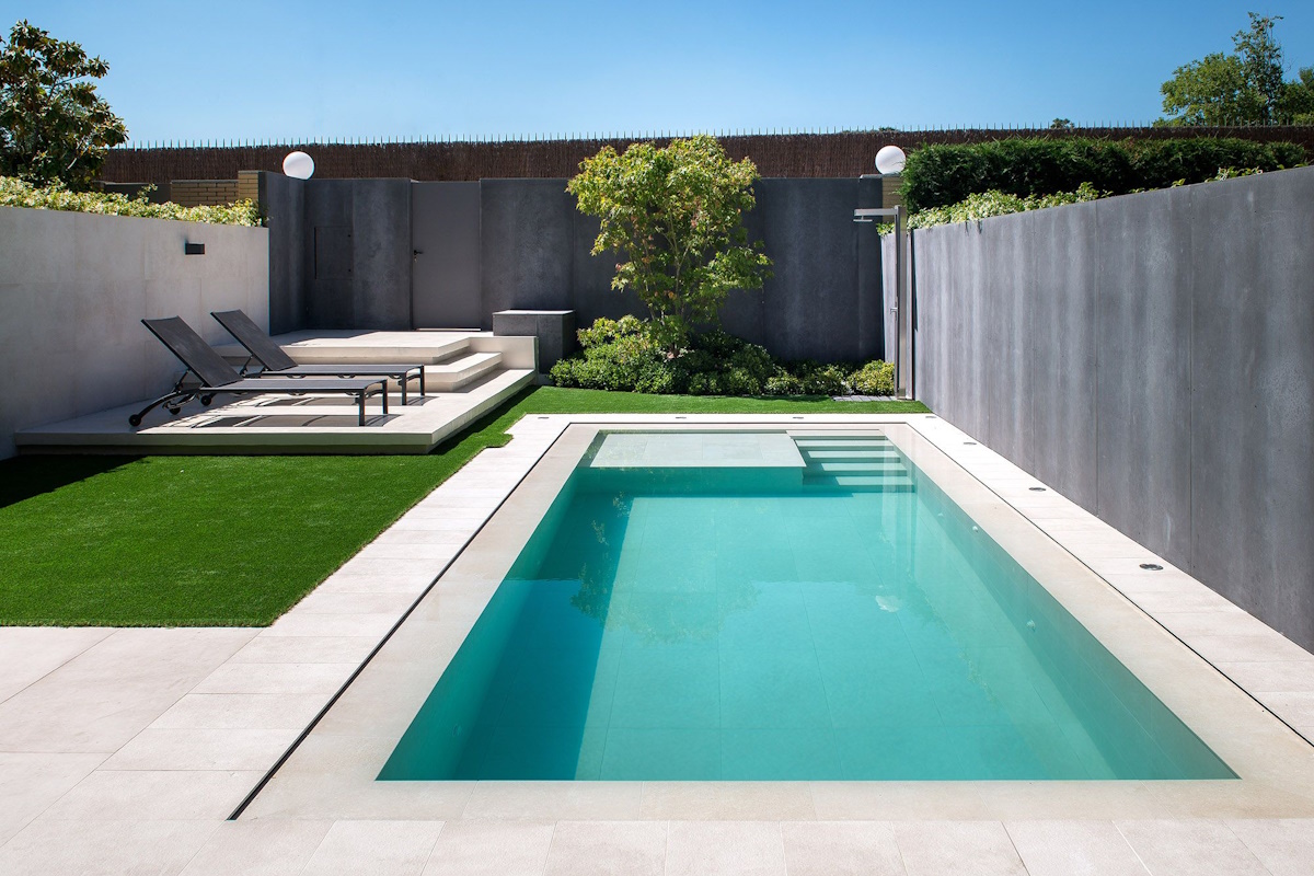 Piscina integrada en el jardín y la terraza de una vivienda